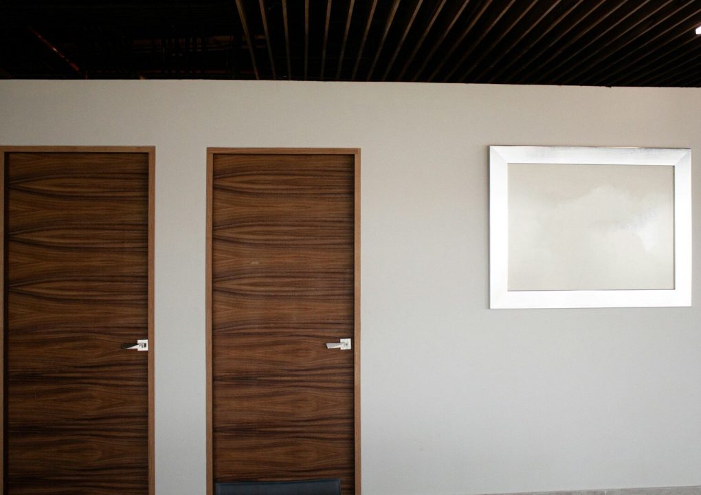 brown wooden door beside white wall