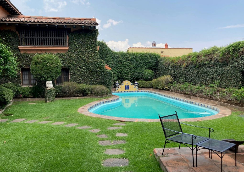 a pool in a yard with a lawn chair next to it